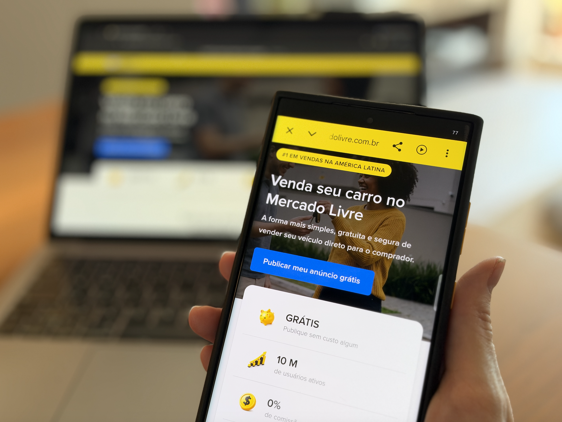 Sell your car landing in Portuguese on a handheld mobile device, with a laptop in the background.
