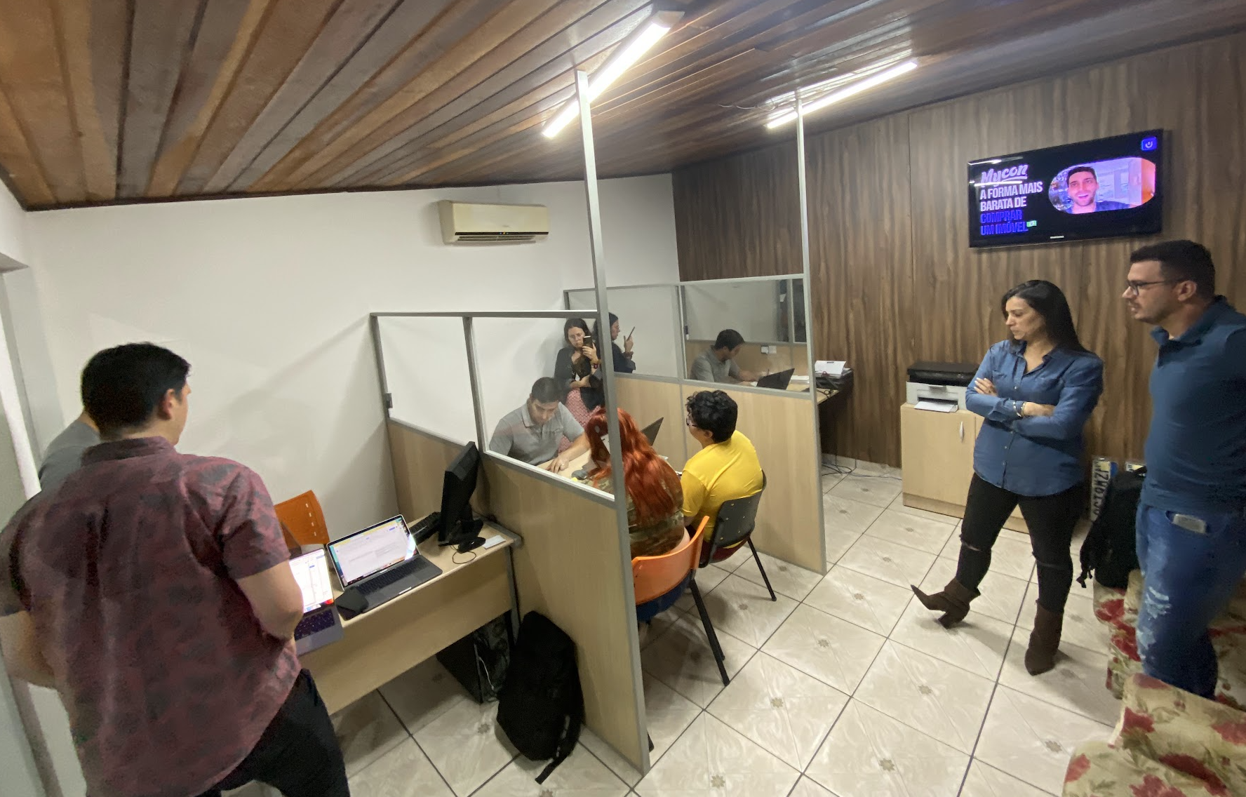 People gathered around workstations in a dealership, with others observing the session.